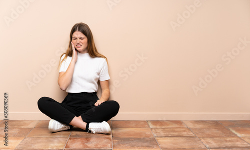 Ukrainian teenager girl sitting on the floor with toothache