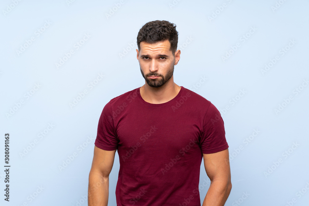 Fototapeta premium Handsome man over isolated blue background with sad and depressed expression