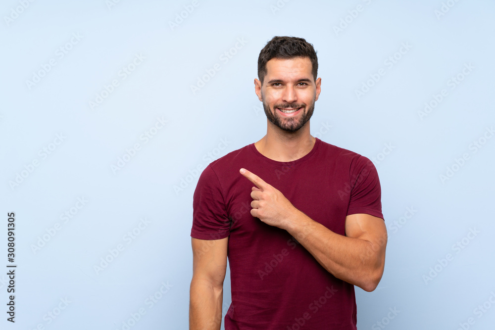 Handsome man over isolated blue background pointing to the side to present a product Handsome man over isolated blue background pointing to the side to present a product