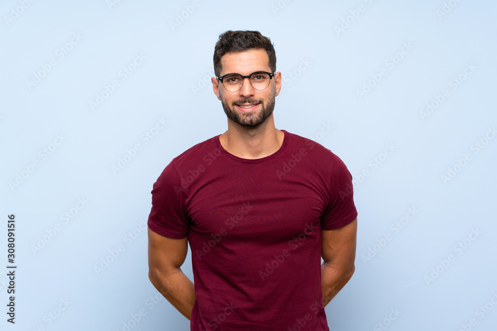 Handsome man over isolated blue background with glasses and happy Handsome man over isolated blue background with glasses and happy