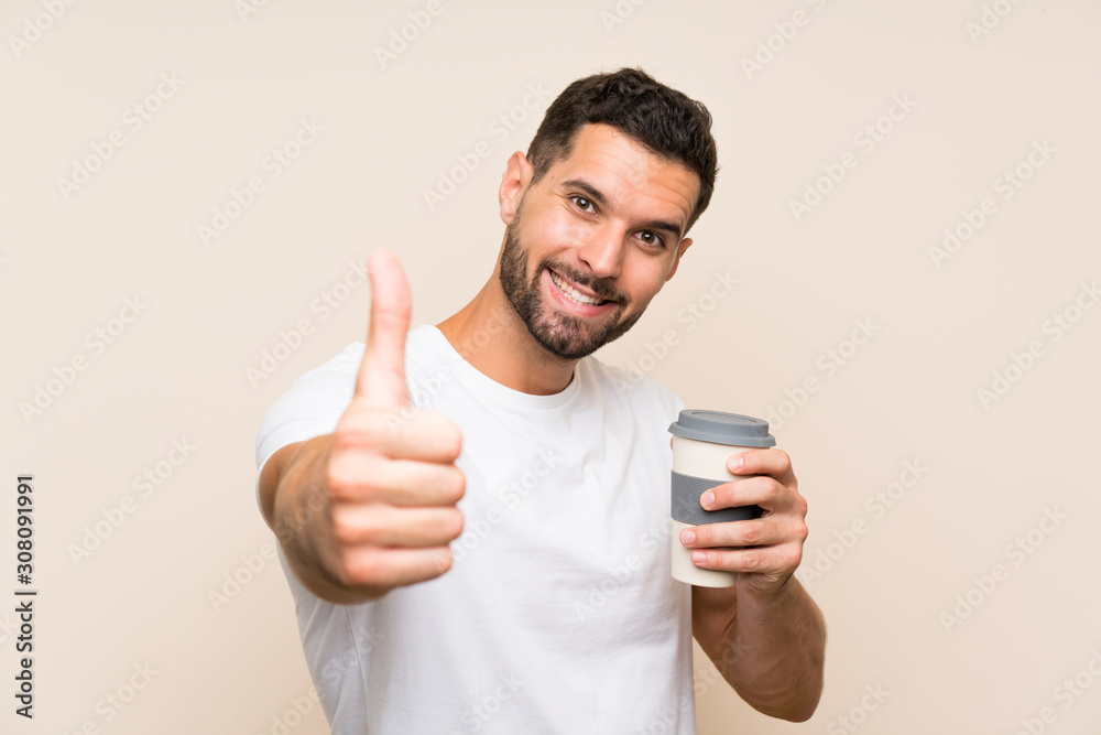 Young man with beard holding a take away coffee over isolated blue background with thumbs up because something good has happened Young man with beard holding a take away coffee over isolated blue background with thumbs up because something good has happened
