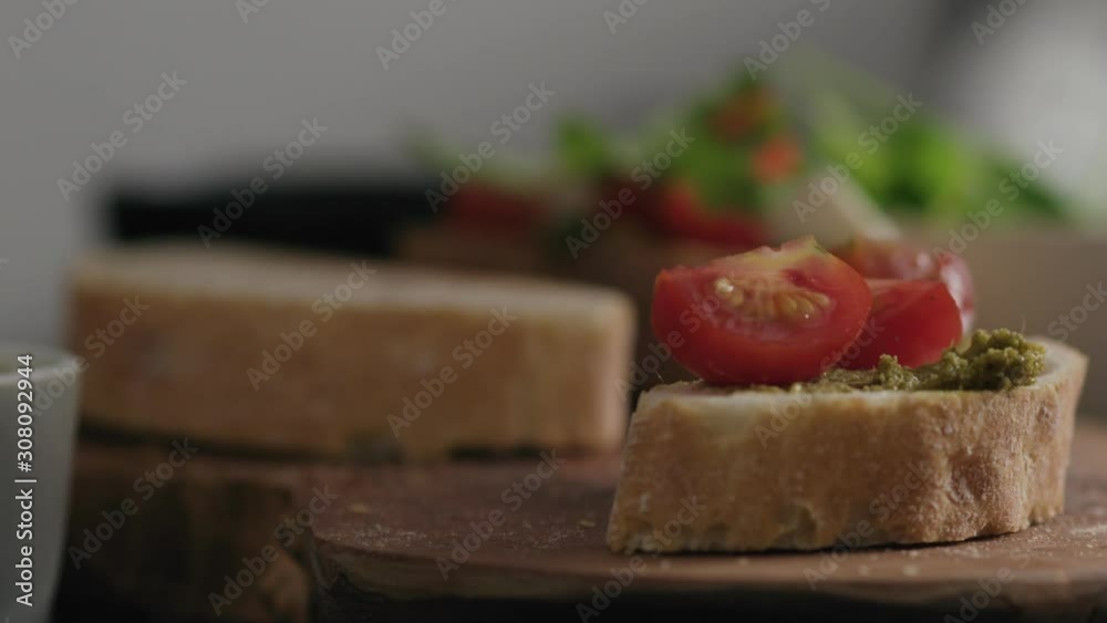 Slow motion closeup man hands making bruschetta with pesto, mozzarella and tomatoes Slow motion closeup man hands making bruschetta with pesto, mozzarella and tomatoes