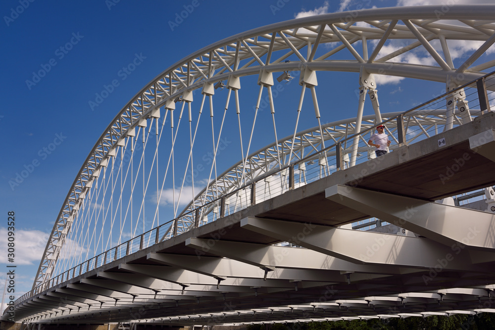 Jogger on new Strandherd Armstrong steel suspension bridge over the Rideau River Ottawa