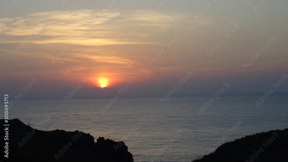 sonnenuntergang mit wolkenschleiern an der felsenküste bei almeria