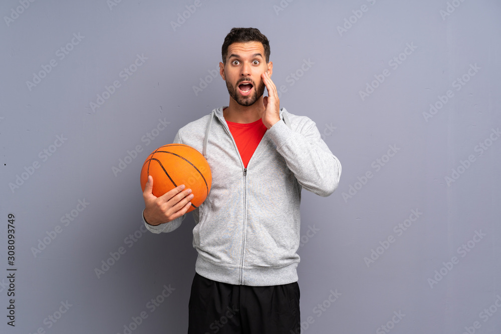 Handsome young basketball player man with surprise and shocked facial expression