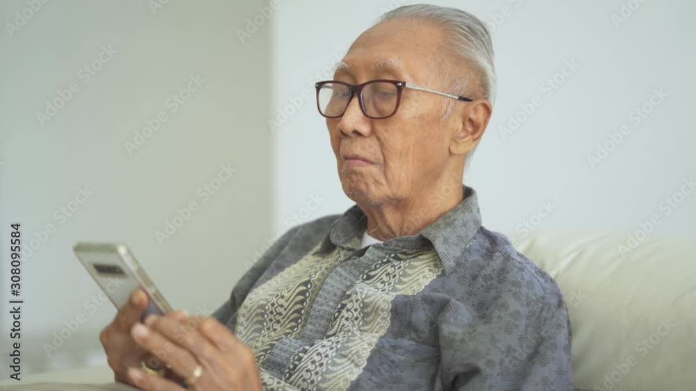 Close up of old man using a mobile phone on couch