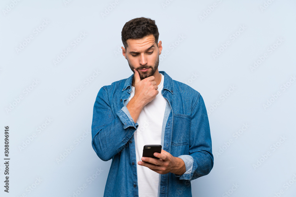Handsome man over isolated blue background thinking and sending a message Handsome man over isolated blue background thinking and sending a message