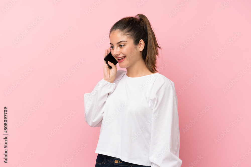 Young brunette girl over isolated pink background keeping a conversation with the mobile phone Young brunette girl over isolated pink background keeping a conversation with the mobile phone