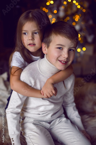 girl hugs her brother sitting on bed in Studio