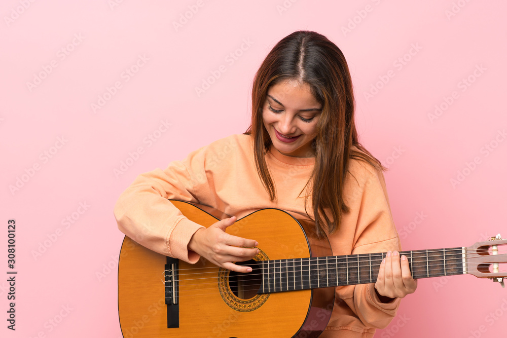 Young brunette girl with guitar over isolated pink background Young brunette girl with guitar over isolated pink background