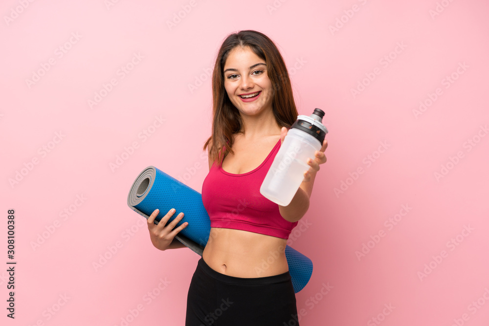 Young sport girl over isolated pink background with sports water bottle and with a mat Young sport girl over isolated pink background with sports water bottle and with a mat