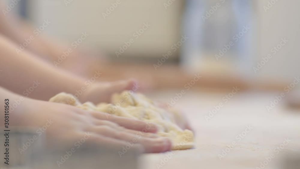 Little daughter helps mom in the kitchen with baking. Knead the dough together. Little daughter helps mom in the kitchen with baking. Knead the dough together.