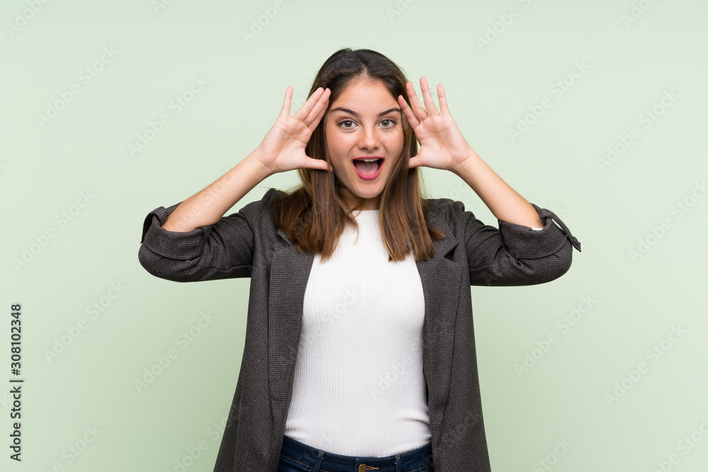 Young brunette girl with blazer over isolated green background with surprise expression Young brunette girl with blazer over isolated green background with surprise expression