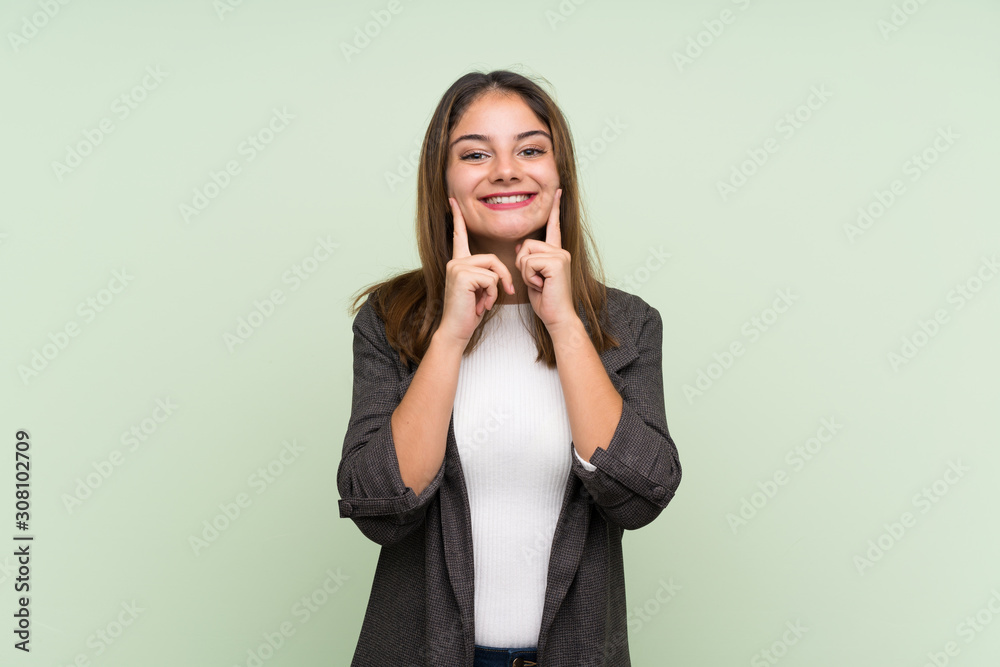 Young brunette girl with blazer over isolated green background smiling with a happy and pleasant expression Young brunette girl with blazer over isolated green background smiling with a happy and pleasant expression