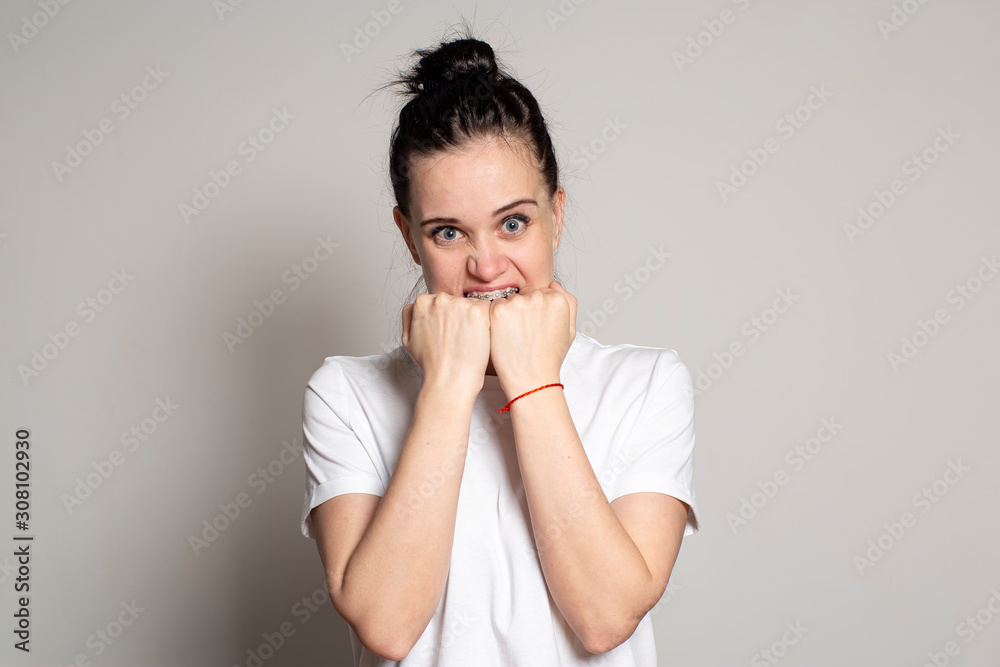 Angry, annoyed woman emotionally bared her teeth, biting her fists and fiercely, with hatred, looks at the camera. Angry, annoyed woman emotionally bared her teeth, biting her fists and fiercely, with hatred, looks at the camera.