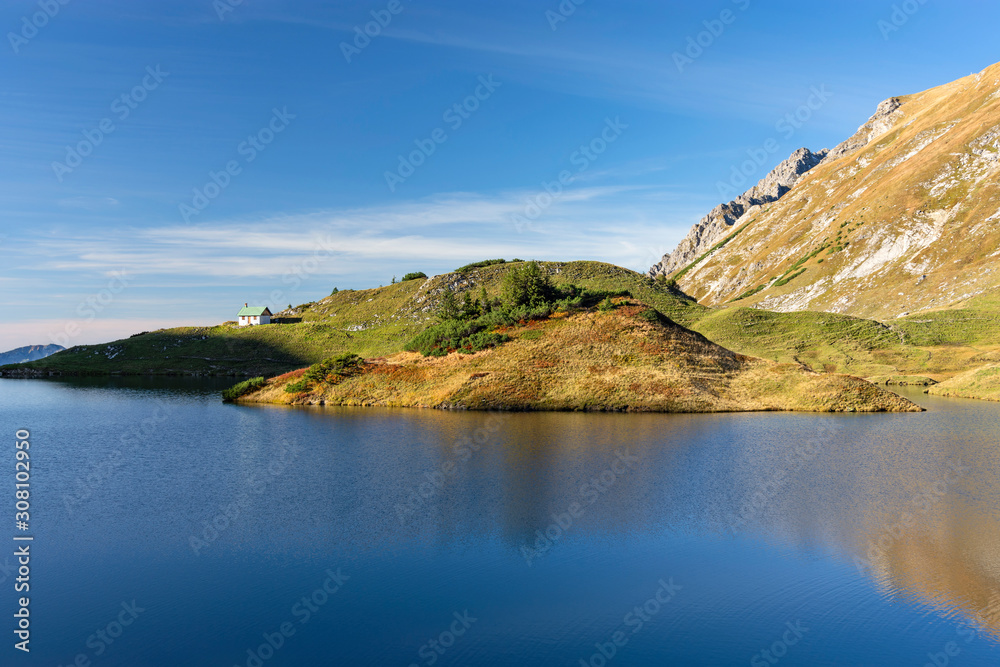 Idyllic mountain lake Schrecksee in late afternoon (Allgau Alps, Bavaria, Germany). Colorful alpine landscape with strong contrast, a little hut and blue sky.