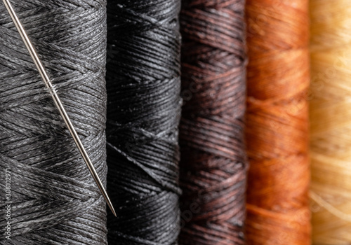 Waxed colorful sewing threads, and needle closeup