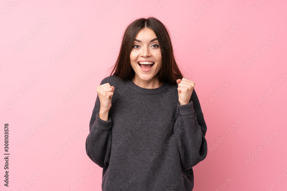Young woman over isolated pink background celebrating a victory in winner position