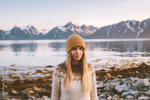 Young woman outdoors travel adventure vacations in Norway sunset mountains and fjord landscape blonde hair scandinavian girl cozy sweater and knitted hat clothing autumn season photo