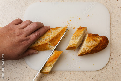 pan baguette de harina cortado a cuchillo encima de tabla de corte, en mármol claro. photo