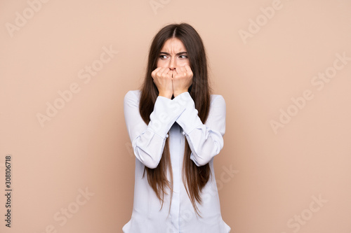 Young woman over isolated background nervous and scared putting hands to mouth