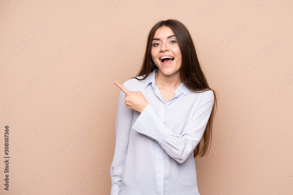 Young woman over isolated background surprised and pointing side Young woman over isolated background surprised and pointing side