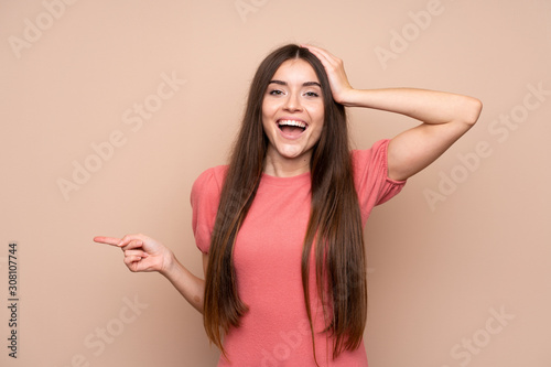 Young woman over isolated background surprised and pointing finger to the side