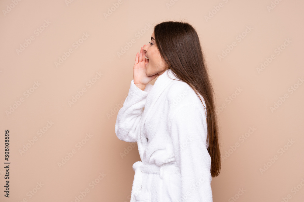Young girl in a bathrobe over isolated background shouting with mouth wide open Young girl in a bathrobe over isolated background shouting with mouth wide open