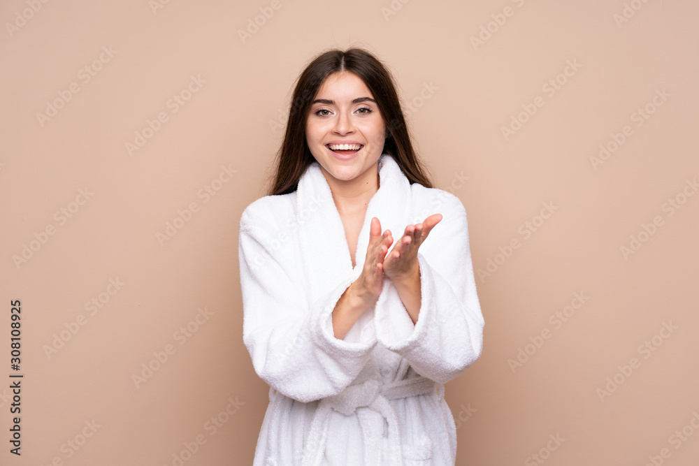 Young girl in a bathrobe over isolated background applauding Young girl in a bathrobe over isolated background applauding