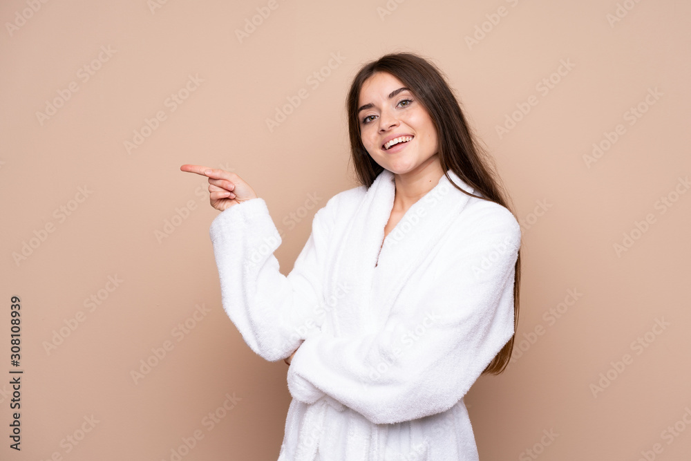 Young girl in a bathrobe over isolated background pointing finger to the side Young girl in a bathrobe over isolated background pointing finger to the side