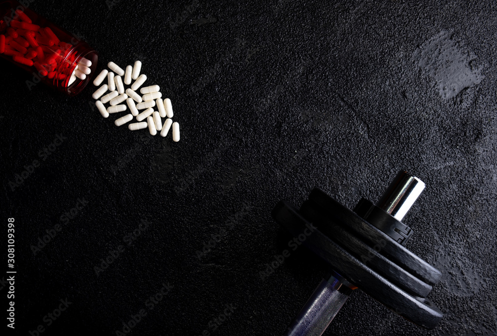 Naklejka premium Sports supplements with weights on dark background. Medicines