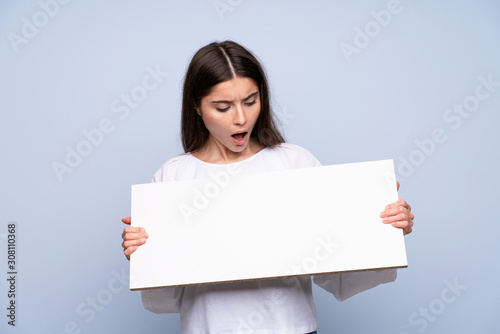 Young woman over isolated blue background holding an empty white placard for insert a concept