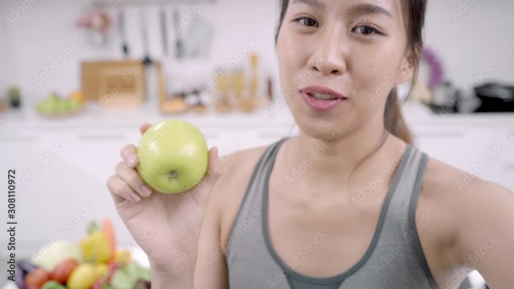 Asian blogger lady make vlog how to diet and lost weight, Young indian female using smartphone recording when she eating apple fruits in the kitchen. Lifestyle influencer women healthy food concept. Asian blogger lady make vlog how to diet and lost weight, Young indian female using smartphone recording when she eating apple fruits in the kitchen. Lifestyle influencer women healthy food concept.