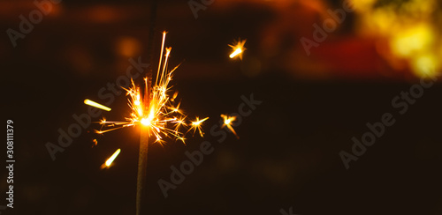 Sparklers for Christmas and New Year close-up on a holiday background in warm colors, wide photo