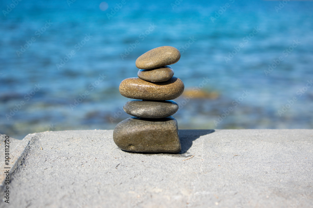 Fototapeta premium Five stones cairn tower, rock zen sculpture, brown beige pebbles and sea light blue background