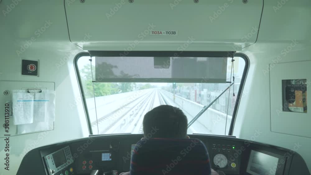 Back view of male train driver sitting in cabin