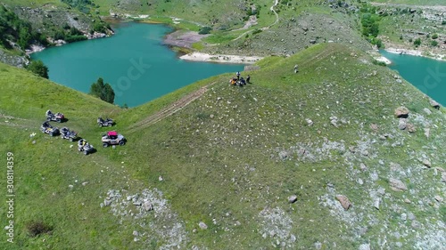 Turquoise lake Giggit and a group of tourists on buggy and Quad Biking. Northern Caucasia. Russia photo