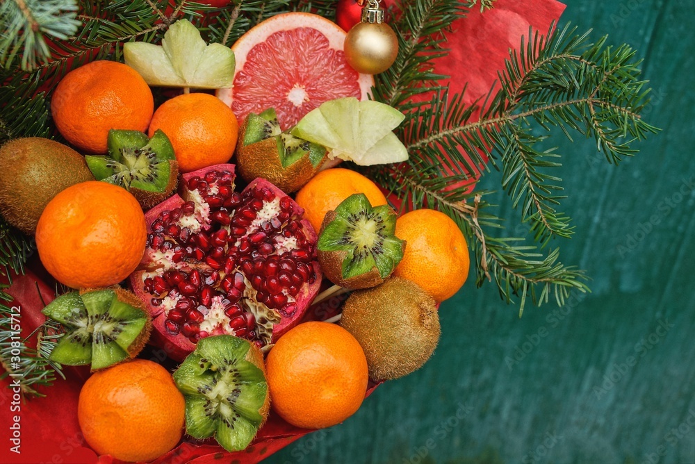 a large bouquet of colored fresh fruits and coniferous branches on a green background a large bouquet of colored fresh fruits and coniferous branches on a green background