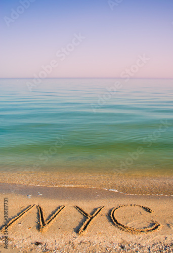 The inscription NYC on sand.  photo