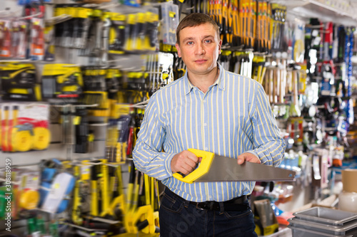 Cheerful male customer choose hacksaw at store