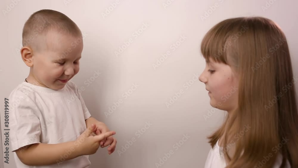 happy children wearing t-shirts play game rock paper scissor on white background, smile and laugh. boy and girl with playing together. little brother and elder sister have fun. small caucasian kids happy children wearing t-shirts play game rock paper scissor on white background, smile and laugh. boy and girl with playing together. little brother and elder sister have fun. small caucasian kids