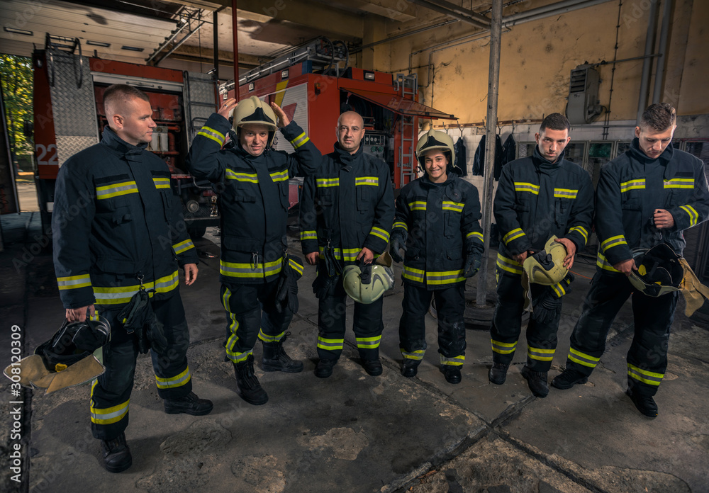 Portrait of firefighters standing by a fire engine. Portrait of firefighters standing by a fire engine.