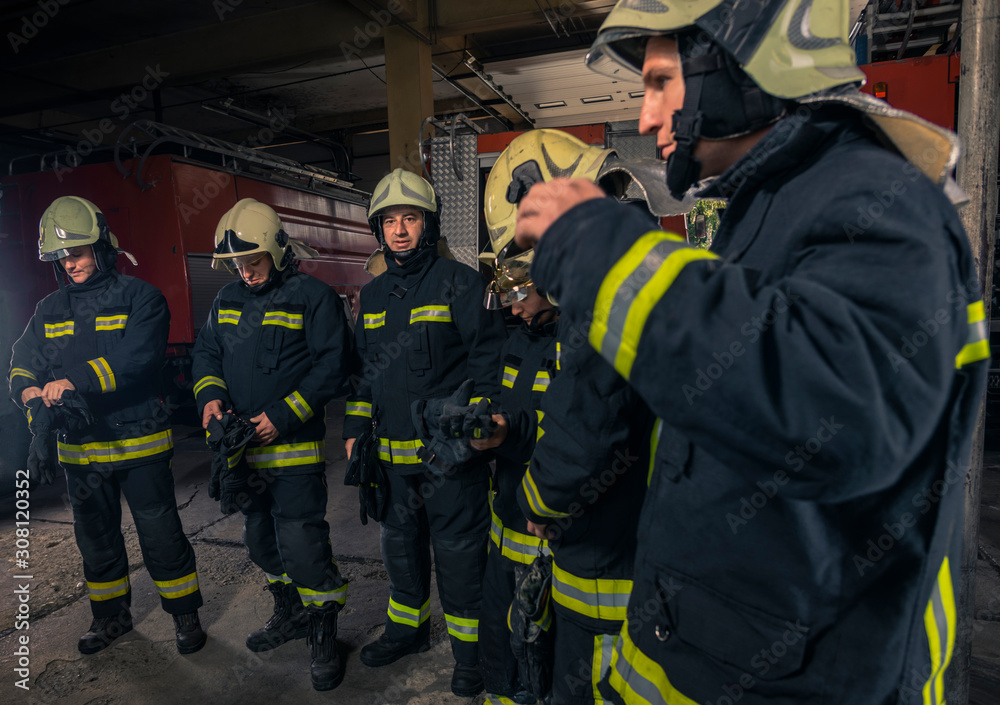 Firemen preparing for emergency service. Firefighters putting on gloves. Firemen preparing for emergency service. Firefighters putting on gloves.