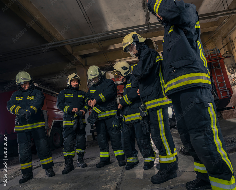 Firemen preparing for emergency service. Firefighters putting on gloves. Firemen preparing for emergency service. Firefighters putting on gloves.