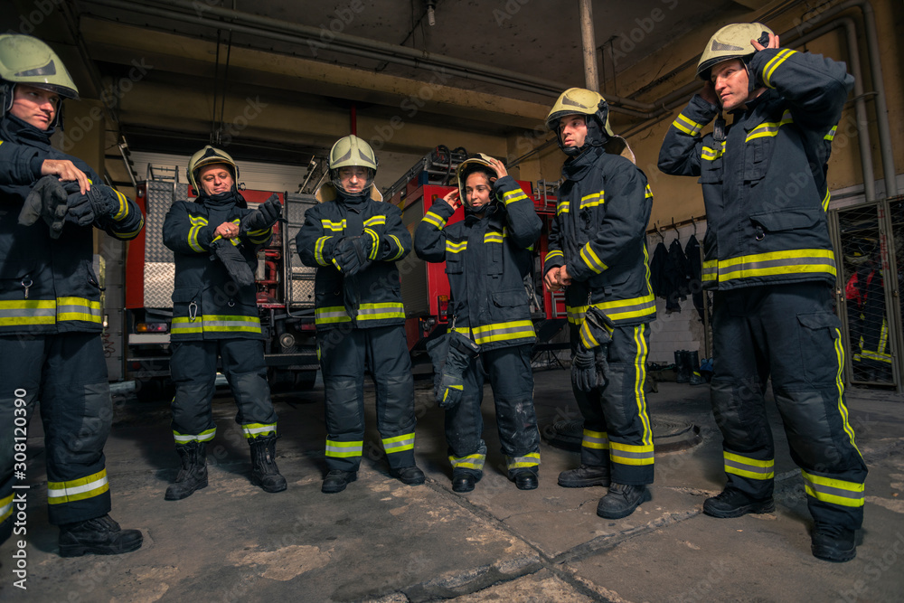 Firemen preparing for emergency service. Firefighters putting on gloves. Firemen preparing for emergency service. Firefighters putting on gloves.