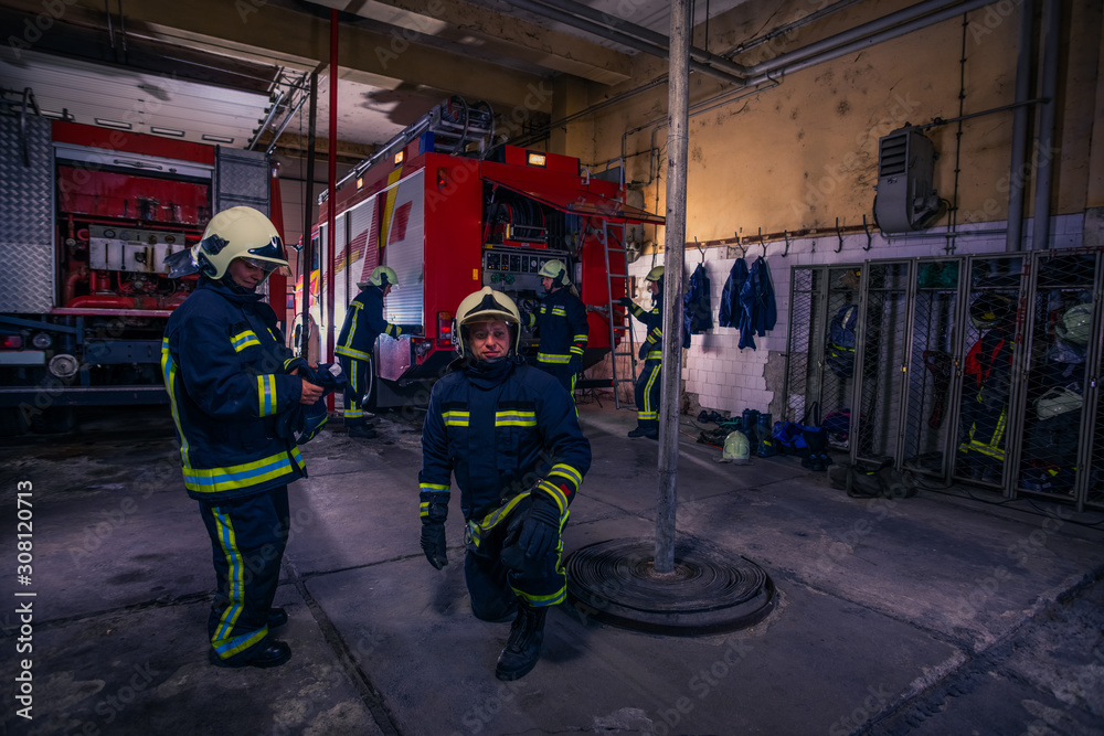 Naklejka premium Firefighters preparing their uniform and the firetruck in the background inside the fire station