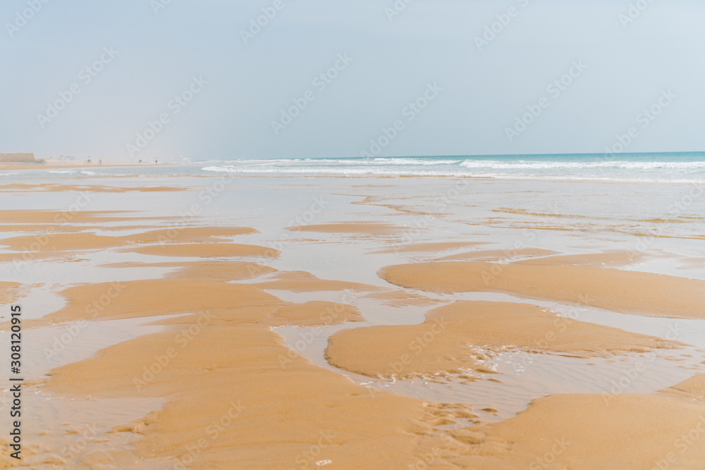 the landscape is a deserted beach, the ocean runs onto the sand and, leaving behind, leaves puddles and sand deposits on it the landscape is a deserted beach, the ocean runs onto the sand and, leaving behind, leaves puddles and sand deposits on it