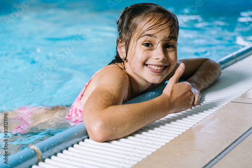 Fototapeta Portrait  little girl having fun in  indoor swimming-pool