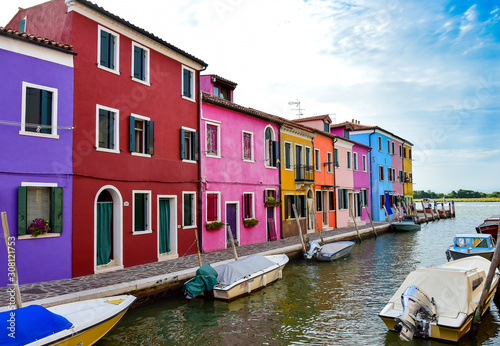 Street with colorful houses, red, yellow, green, blue, canal river with boats, summer, afternoon. Burano, Venice / Italy.