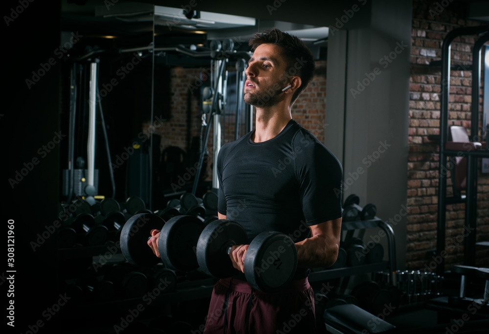 Slim muscular man lifting weights in the gym Slim muscular man lifting weights in the gym